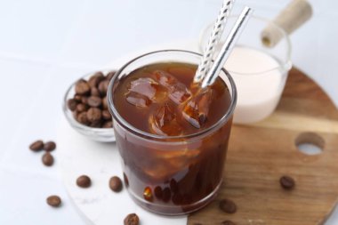 Tasty iced coffee, milk and beans on white table, closeup