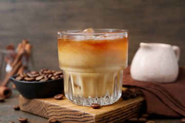 Tasty iced coffee with milk and beans on wooden table, closeup