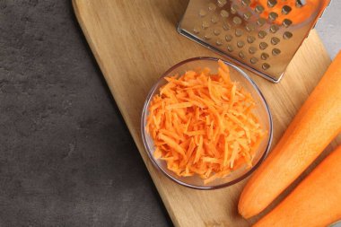 Tam ve rendelenmiş havuç ve rendelenmiş rende gri masada, düz yerde. Metin için boşluk