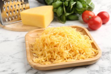 Beyaz mermer masada rendelenmiş peynir, rende ve ürünler, yakın plan.