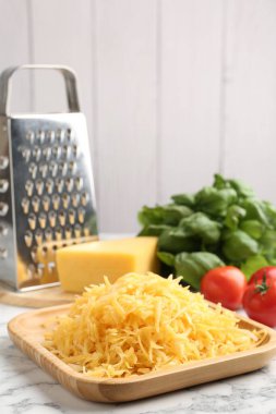 Beyaz mermer masada rendelenmiş peynir, rende ve ürünler, yakın plan.