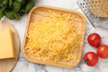 Beyaz mermer masa üzerinde rendelenmiş peynir, rende ve ürünler.