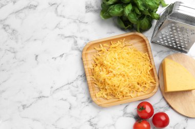 Beyaz mermer masa üzerinde rendelenmiş peynir, rende ve ürünler. Metin için boşluk