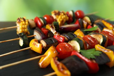 Ahşap masada lezzetli ızgara sebzeli şişler bulanık arka plan, yakın plan