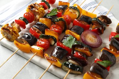 Açık gri masada lezzetli ızgara sebzeli şişler, yakın plan.