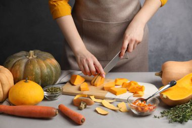 Gri masada balkabağı kesen kadın, yakın plan.