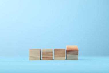 Blank wooden cubes on light blue background, space for text