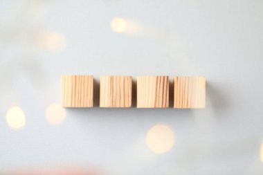 Blank wooden cubes on light grey background, flat lay. Bokeh effect