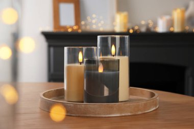 Decorative LED candles on wooden table at home, closeup. Bokeh effect