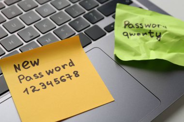 Şifre değiştiriliyor. Yeni ve eski şifreli kâğıt notlar ve beyaz masada dizüstü bilgisayar