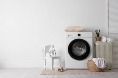 Çamaşır makinesi, sepeti ve çiçekli iç çamaşır odası. Metin için boşluk