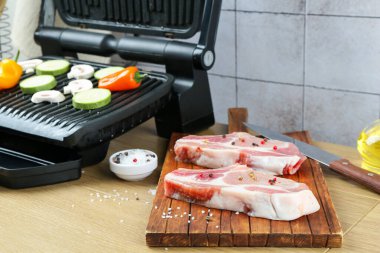 Sebzeli ızgara, mantarlı ve ahşap masada çiğ et, yakın plan.