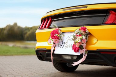 Düğün arabası. Cabriolet dekore edilmiş. Sadece evlilik kartı ve açık havada güzel çiçekler, yakın plan.