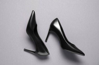 Açık gri arka planda bir çift şık siyah topuklu, üst manzara. Şık ayakkabılar.