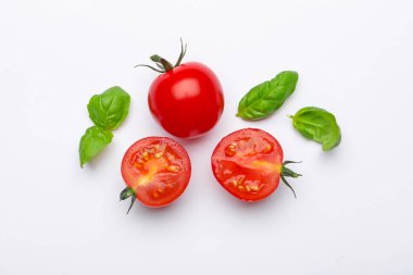 Beyaz arka planda taze kırmızı domates ve fesleğen yaprakları.