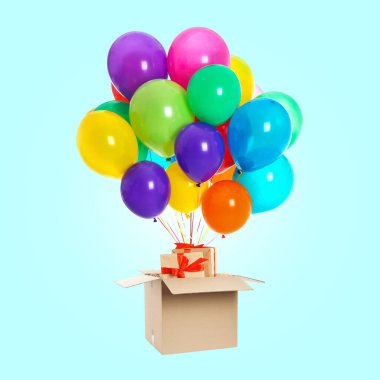 Tatil teslimatı. Hava balonları açık mavi arka planda paketten dışarı uçuyor.