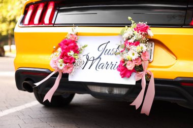 Düğün arabası. Cabriolet dekore edilmiş. Sadece evlilik kartı ve açık havada güzel çiçekler, yakın plan.