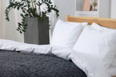 Temiz beyaz çarşaflar ve gri battaniyeli yatak, yakın plan.