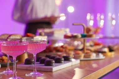 Different delicious desserts, drinks on buffet table and waiter, selective focus