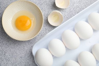 Bir sürü çiğ tavuk yumurtası ve bir tanesinin kasesi gri masada kırılmıştı.