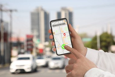 Şehir caddesinde taksi çağırmak için cep telefonu uygulaması kullanan bir adam.