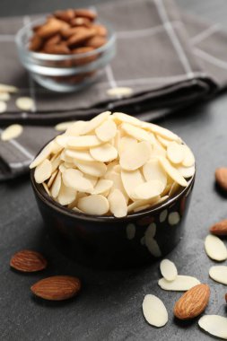 Taze badem gevrekleri kasede ve fındıklar gri masada, yakın plan.