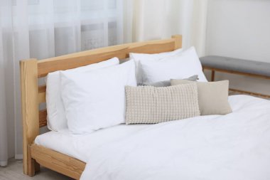 Bed with fresh white linens indoors, closeup