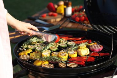 Vejetaryen barbeküsü. Dışarıdaki ızgarada sebze pişiren kadın, yakın plan.