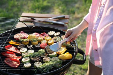 Vejetaryen barbeküsü. Dışarıdaki ızgarada sebze pişiren kadın, yakın plan.