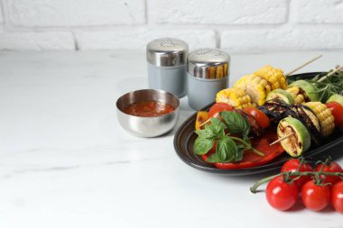 Vejetaryen barbeküsü. Beyaz mermer masada servis edilen lezzetli ızgara sebzeler, yakın plan. Metin için boşluk