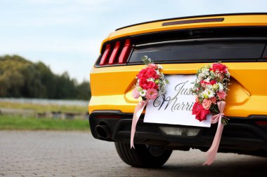 Düğün arabası. Cabriolet dekore edilmiş. Sadece evlilik kartı ve açık havada güzel çiçekler, yakın plan.