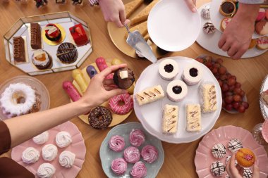 İnsanlar açık büfeden farklı tatlılar yiyorlar.