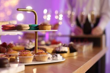 Different delicious desserts on buffet table and waiter, selective focus