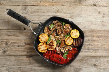 Ahşap masada nefis ızgara sebzeler, mantarlar ve maydanoz.