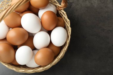 Hasır sepetin içinde çiğ tavuk yumurtası, gri masanın üstünde, üst manzara. Metin için boşluk