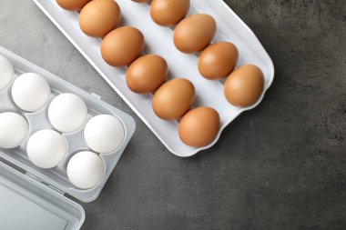 Gri masadaki plastik kaplarda çiğ tavuk yumurtası. Metin için boşluk