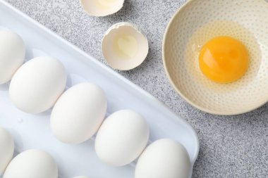 Bir sürü çiğ tavuk yumurtası ve bir tanesinin kasesi gri masada kırılmıştı.