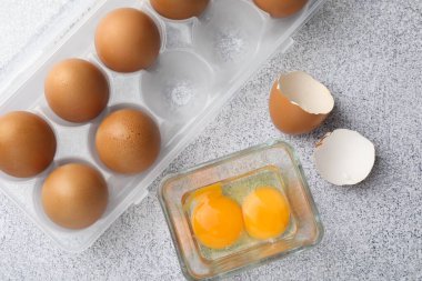 Bir sürü çiğ tavuk yumurtası ve kırık yumurta gri masada, düz yatıyordu.