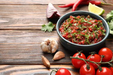 Tasty salsa sauce and ingredients on wooden table, closeup. Space for text