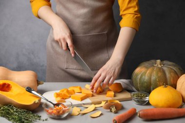 Gri masada balkabağı kesen kadın, yakın plan.