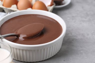 Kase içinde sıvı çikolata hamuru ve gri masadaki malzemeler, yakın plan. Metin için boşluk