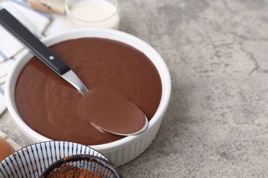 Gri masadaki kasede sıvı çikolata hamuru, yakın plan. Metin için boşluk