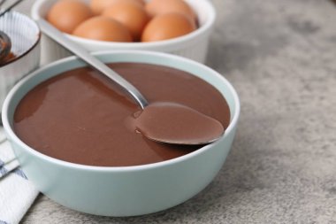 Kase içinde sıvı çikolata hamuru ve gri masadaki malzemeler, yakın plan. Metin için boşluk