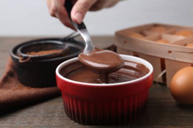 Tahta masadaki kasede çikolata hamuru olan kadın, yakın plan.