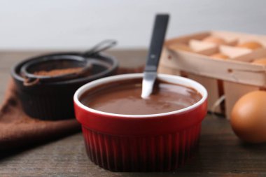 Sıvı çikolata hamuru kasede ve malzemeler ahşap masada, yakın plan.