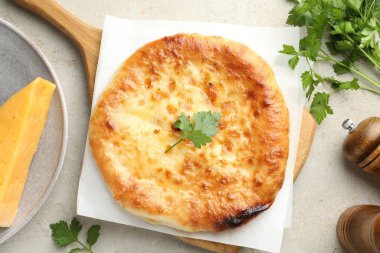 Delicious Megrelian khachapuri with ingredients on grey table, flat lay