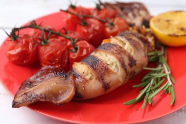 Lezzetli kalamar, biberiye, limon ve domatesler beyaz masada, yakın plan.