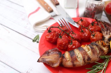 Tasty stuffed squid, rosemary and tomatoes on light wooden table, closeup. Space for text