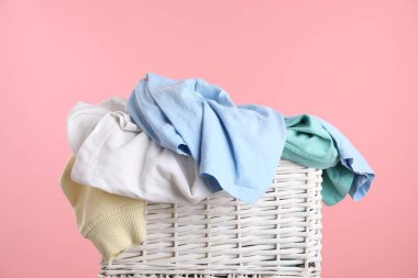 Pembe arka planda giysileri olan çamaşır sepeti, yakın plan.