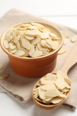 Fresh almond flakes on white wooden table, closeup